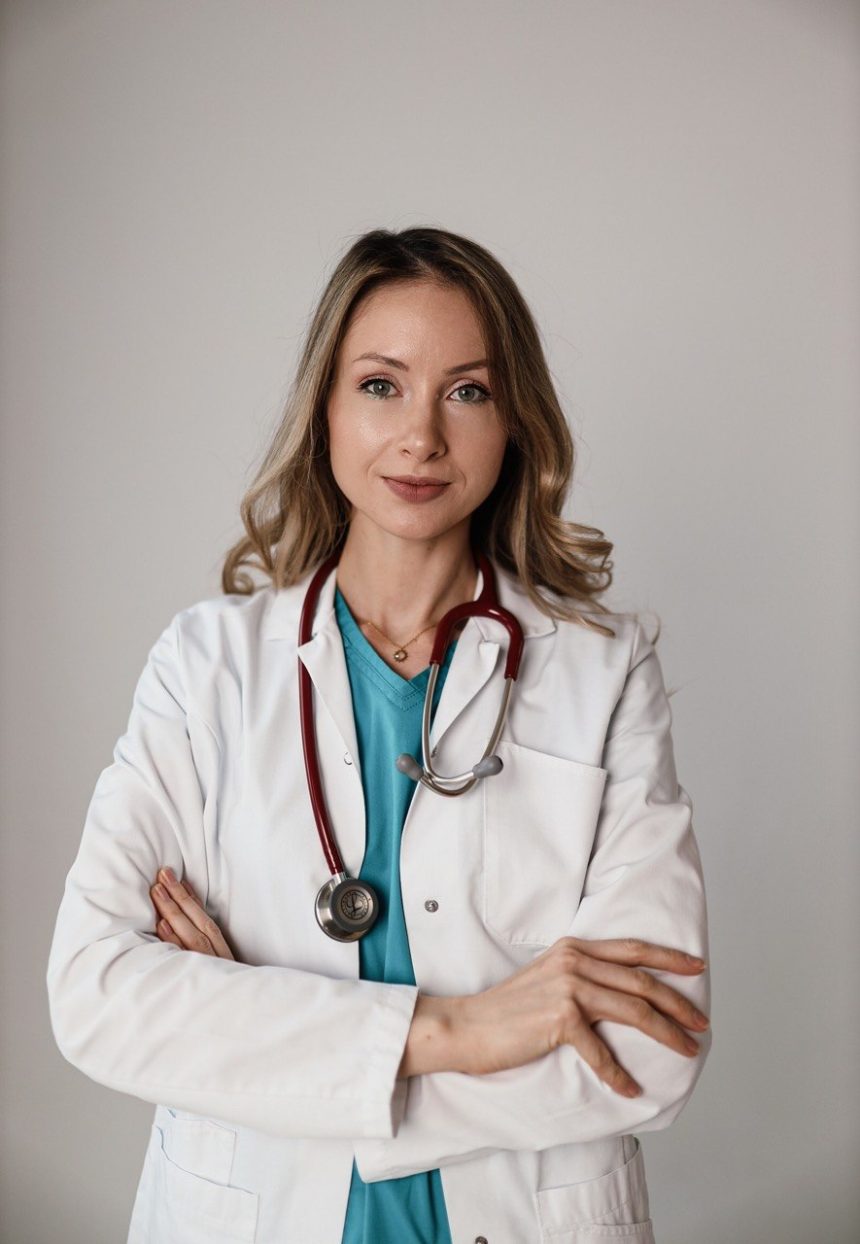 Dr. Elena Pușca, în halat alb, cu stetoscopul la gât și brațele încrucișate